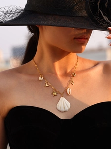 Close-up of gold ocean theme necklace featuring shell, turtle and whale tail charms