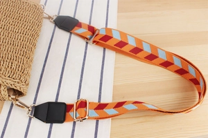 Detail of adjustable woven crossbody strap with geometric pattern and gold hardware