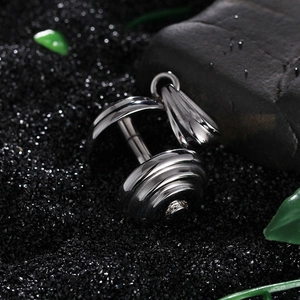 Vue macro d'un pendentif haltère en acier inoxydable poli sur fond texturé noir