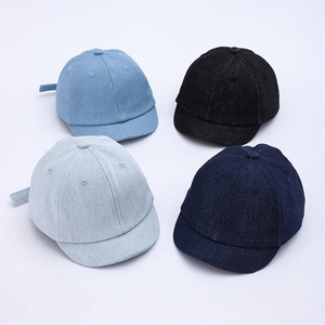 Flat lay of four denim baby baseball caps in light blue, black, grey-blue, and navy navy