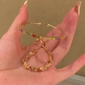Dettaglio di un set di bracciali dorati con strass multicolori scintillanti