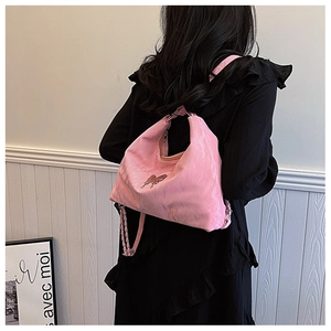 Pink pleated tote bag with chain strap and bow detail worn by a model in a minimal setting