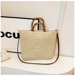Detail of woven straw bag featuring a natural bamboo handle and brown leather strap