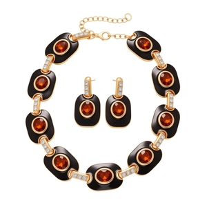 Vintage gold jewelry set with orange gemstones and black enamel oval necklace and earrings