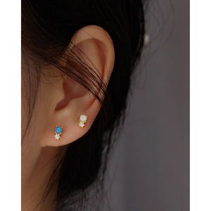 Detailed close-up of blue and white opal earrings with small diamonds on ears