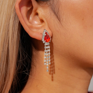 Macro shot of elegant silver drop earrings with red pear-shaped stones and tassels