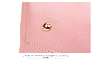 Close-up of pink litchi leather bag bottom with gold rivets and reinforced stitching