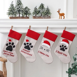 Set of four beige Christmas stockings with pet paw prints and holiday puns on a mantel