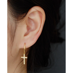 Close-up of gold S925 silver cross earring with shimmering crystals on ear lobe