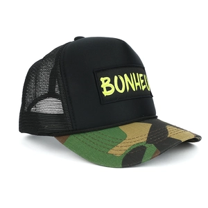 Detail view of trucker hat with neon green Bonheur text and camouflage brim