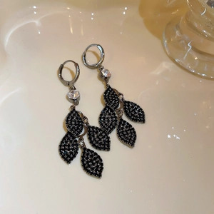 Detail of silver needle earrings with black micro-inlaid zircon and layered leaf tassels