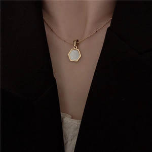 Detail view of gold titanium steel necklace with a white hexagonal mother of pearl pendant