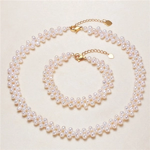 Detail of white pearl necklace and bracelet set with golden lobster clasp and heart charm