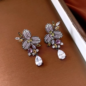 Dettaglio di orecchini vintage a fiore con pietre viola e un grande zircone a goccia