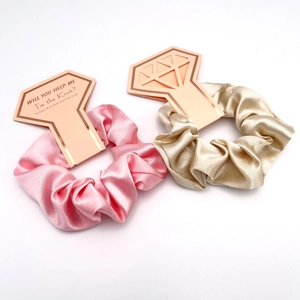 Pink and gold silk scrunchies with diamond-shaped bridesmaid gift cards for wedding