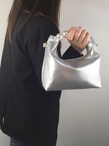 Close-up of metallic silver pillow bag featuring elegant white pearl handle and gold hardware