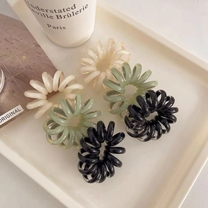 Set of 6 jelly color spiral hair ties in matte black, green, and cream on a tray