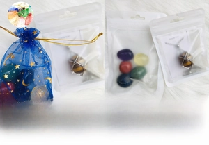 7 Chakra crystal set featuring raw stones and a metal cage pendant on plush background