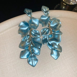Detail of blue layered petal fringe earrings with golden chains on a textured plate