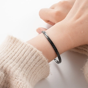 Close-up of black titanium steel chain bracelet worn on a woman's wrist in a modern style