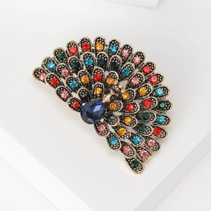 Macro view of crystal peacock brooch showing colorful rhinestones and gold-plated finish
