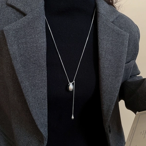 Minimalist silver teardrop pendant necklace worn over a professional gray wool blazer