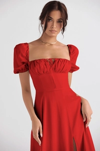 Detail view of red puff sleeves, pleated square neckline, and lace-up design on dress