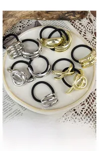 Detailed close-up of vintage geometric metal charms on elastic hair ties in a dish