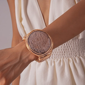 Artistic gold multi-layer wire cuff bracelet with textured metallic disc on female wrist