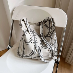Detail of minimalist floral print canvas tote bag resting on a white modern chair