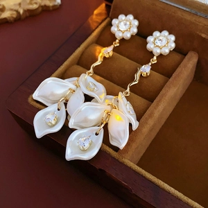 Macro detail of petal pearl tassel earrings with gold accents and sparkling cubic zirconia