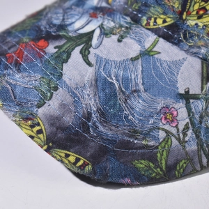 Macro shot of distressed denim fabric with floral print and frayed edge detail
