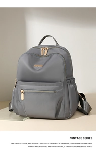 Detail view of the gray nylon backpack with golden zippers and multi-layer storage compartments