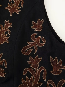 Gros plan sur la broderie florale marron d'un gilet noir en daim de style ethnique