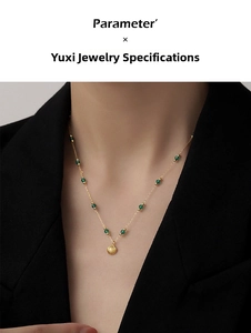 Detail view of a shell pendant necklace with green beads on a gold chain