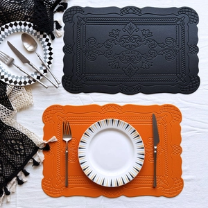 Detail of vintage embossed faux leather placemats with scallop edges in black and orange
