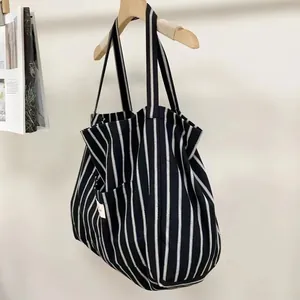 Detail of high-density canvas tote featuring vertical black and white stripes and side woven label