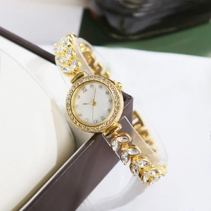Detail of gold women's watch featuring a white dial and leaf-shaped diamond-set band