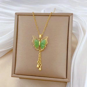 Detail of gold necklace with green butterfly pendant and tassel on white silk