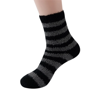 Detailed view of men's black and grey striped coral fleece socks worn by a model