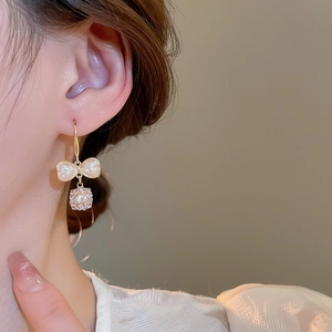 Detail of bow earrings with iridescent mother-of-pearl and sparkling zircon pendant