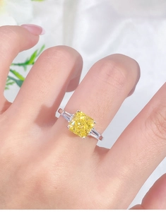 Macro view of luxury square yellow diamond ring with emerald cut side stones on silver band