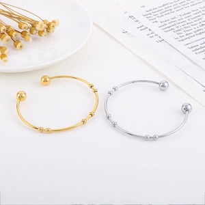 Minimalist gold and silver open bangles with movable beads on a clean aesthetic background