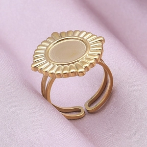 Close-up of golden stainless steel sunburst ring on elegant purple satin background