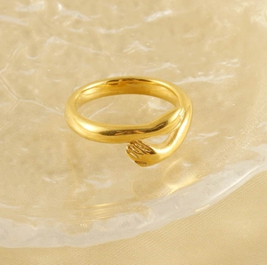 Macro shot of polished 18k gold plated stainless steel ring with hugging hands design
