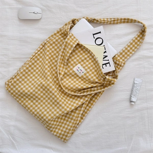Macro detail of yellow plaid fabric tote bag with colorful label on white background