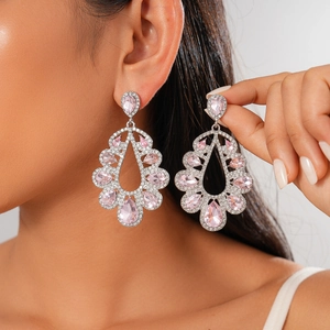Luxury silver-tone drop earrings with pink pear-shaped crystals worn by a model