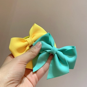 Detail of ribbed texture and fabric layers on yellow and mint green bow hair clips