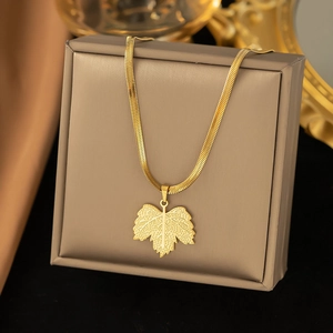 Macro detail of golden leaf pendant and sleek snake chain on premium jewelry box