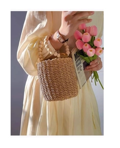 Detailed texture of straw bucket bag with elegant wooden beaded handle for summer beach style